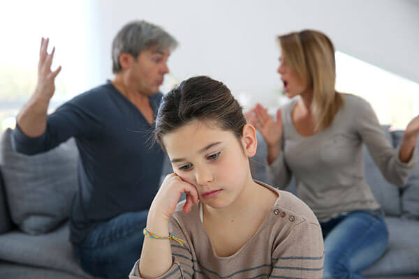 Sad child with parents arguing who need a family disputes resolution.